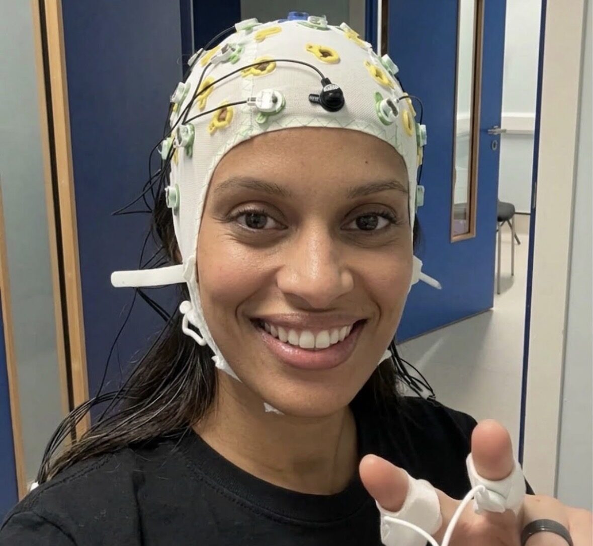 Ashlei Lewis in a white EEG cap with electrodes during a lab session.